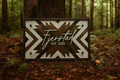 Decorative sign with geometric pattern and text 'Fjerstad EST 2001' in a forest setting