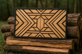 Wooden geometric patterned box on stacked logs with a blurred forest background