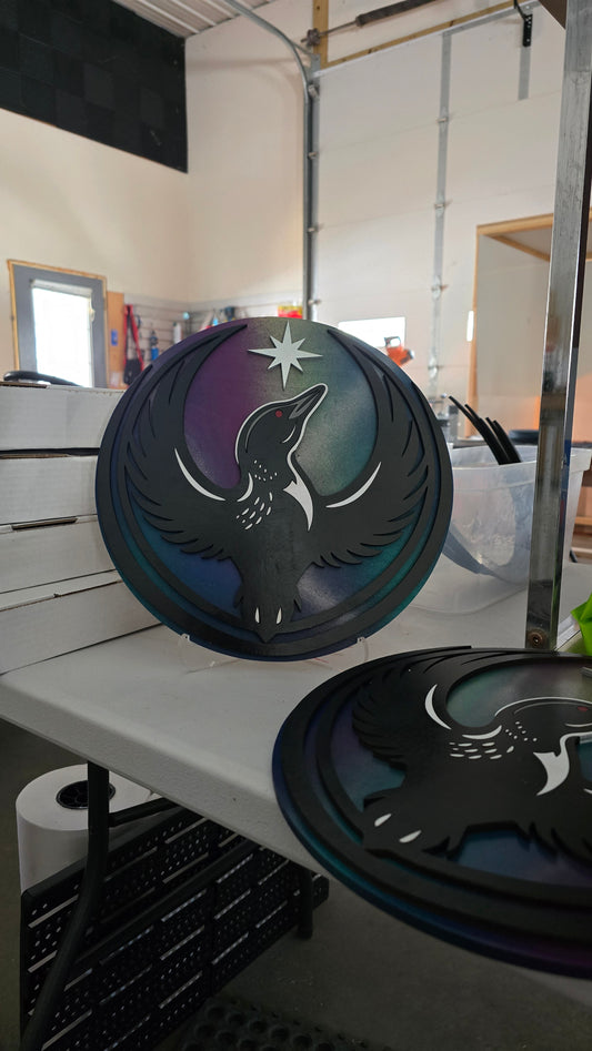 Rebel Loon wood signs with an iridescent Northern Lights painted backer, shown in the workshop